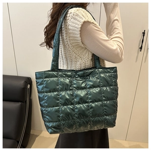 Detail view of large dark green quilted puffer tote bag with glossy metallic finish