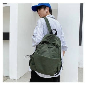 Detail of dark green backpack in crinkled nylon fabric shown on model in sunlight