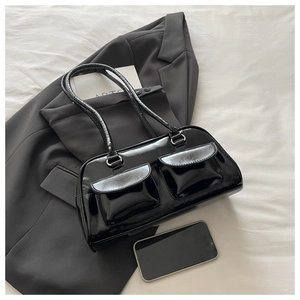 Detail of black patent leather baguette bag with double front flap pockets and silver hardware