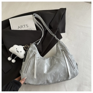 Detail of silver metallic tote bag with wrinkled PU texture and cloud plush pendant