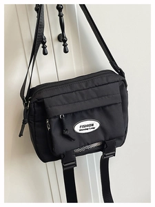 Detail of black nylon crossbody bag with adjustable strap and front buckle pocket