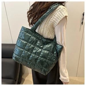 Detail view of large green glossy quilted tote bag with stitched square pattern