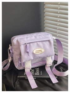 Detail view of purple canvas crossbody bag featuring a front mesh layer and white buckle flap