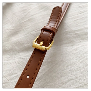 Détail de la bandoulière en cuir marron avec boucle en métal doré et coutures nettes