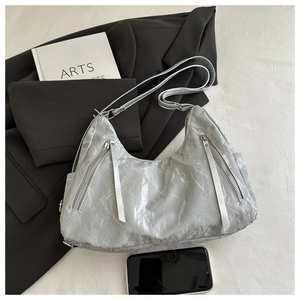 Detail of silver metallic hobo bag featuring crinkled texture and long tassel zippers