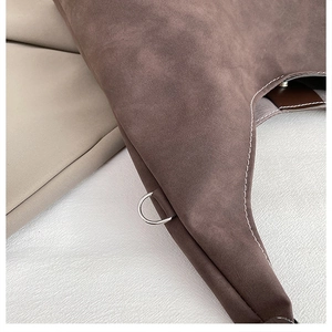 Dettaglio della borsa tote in pelle scamosciata marrone con cuciture bianche e fibbia a D