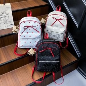 Three stylish bow backpacks with leopard bear charms on wooden stairs in white, black and silver