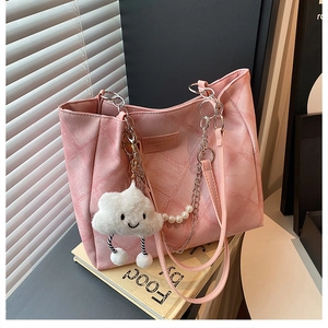 Detail of pink quilted tote bag featuring pearl chain strap and fluffy cloud pendant
