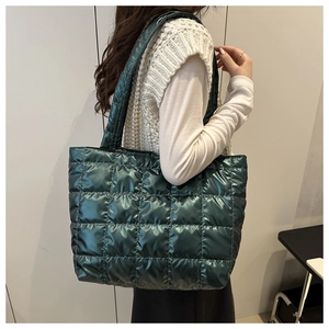 Detail of dark green metallic quilted tote bag with glossy finish and wide shoulder strap