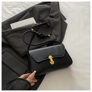 Detail of matte black leather handbag with gold metal lock and knotted cord strap