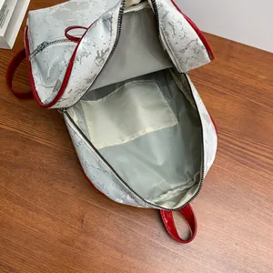 Fashionable bow backpack with silver textured finish and red trim, showing internal storage