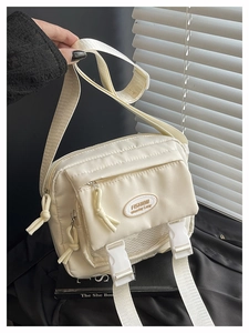 Detail of the cream nylon crossbody bag with adjustable strap and front buckle closure
