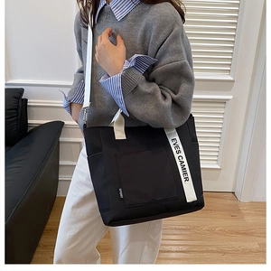 Minimalist black canvas tote bag with adjustable shoulder strap and logo detail