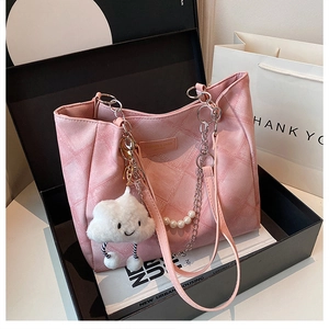 Detailed macro view of pink quilted tote bag with gold chain strap and pearl decor