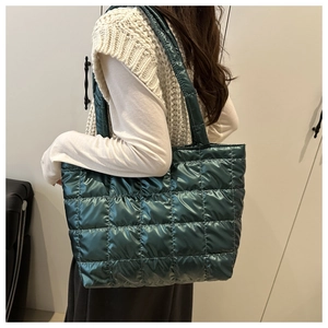 Detail view of dark green quilted tote bag with metallic gloss finish and wide straps