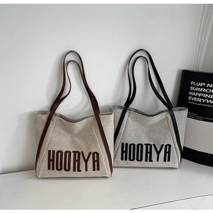 Detail view of durable canvas tote bags with HOORYA lettering in beige and grey colors