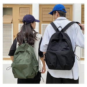 Large military green and black nylon backpacks shown on models in a casual city setting