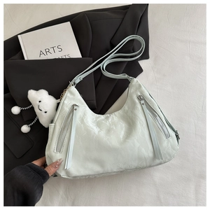 Detail of mint green crescent bag with mica texture and plush cloud charm on a blazer