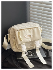 Detail of cream white nylon crossbody bag featuring multi-pocket design and resin buckles