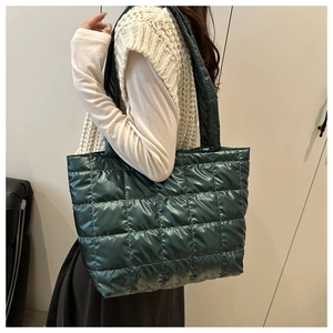 Detail view of large dark green quilted tote bag with metallic glossy fabric for women