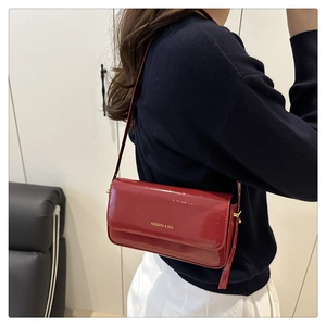 Detailed view of the red glossy patent leather rectangular handbag with gold metal hardware
