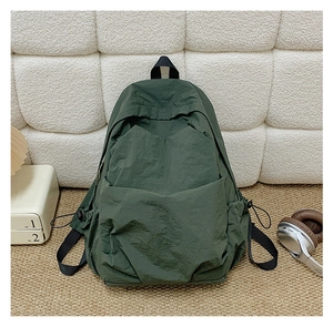 Detail of dark green nylon backpack featuring side drawstring and front storage pocket