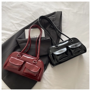 Close-up of glossy leather baguette bags in burgundy and black with buckled pocket detail