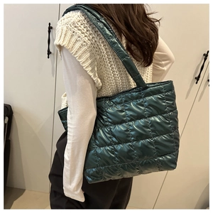 Detail of dark green quilted tote bag with a metallic glossy finish and puffer texture