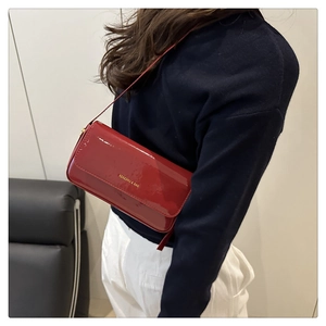 Model wearing a red patent leather rectangular crossbody bag with golden logo detail