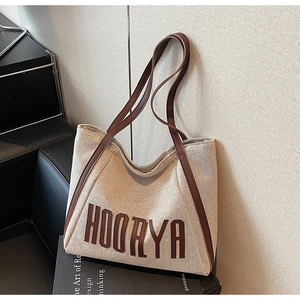 Close-up of Hoorya canvas tote bag showing dark brown leather trim and letter stitching