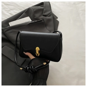 Detail of elegant black leather handbag featuring a polished gold oval metal buckle