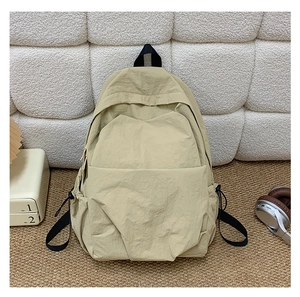 Detail of khaki nylon backpack featuring drawstring side pockets and utility workwear style
