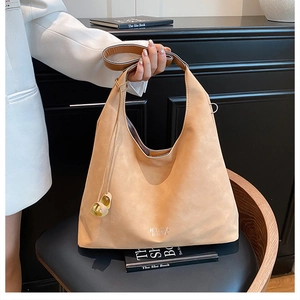 Dettaglio macro della borsa tote in camoscio cammello con texture morbida e fibbia