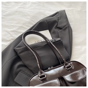 Detail of dark brown polished leather shoulder bag with two front magnetic pockets and silver rings