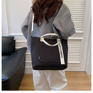 Rear view of a casual black canvas tote bag with contrast sport-style lettered straps