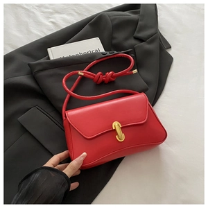 Detail of red leather crossbody bag featuring a golden metal buckle and flap closure