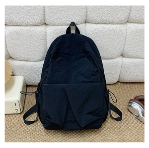 Detail view of large black nylon backpack with side drawstring pockets on woven rug