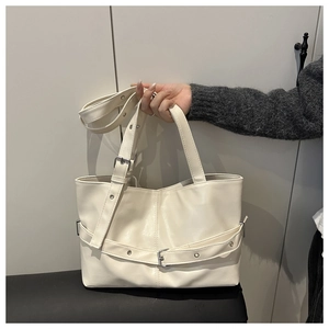 Detailed macro view of the beige tote bag featuring decorative belt and metal hardware buckle
