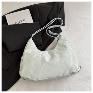Detail of light green crescent underarm bag with pleated texture on black blazer background