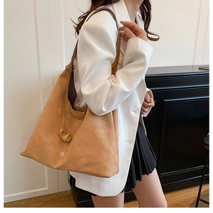 Dettaglio della borsa tote in pelle scamosciata cammello con logo HY LC e tracolle