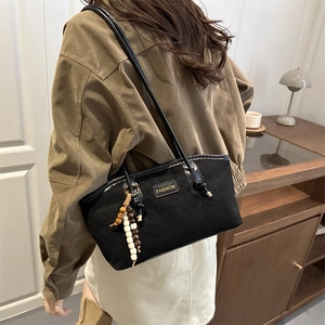 Black canvas tote bag with fashion tag and wooden bead tassel in a stylish shoulder view