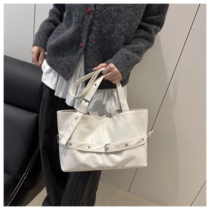 Detail view of beige tote bag with decorative belt buckle and adjustable shoulder strap