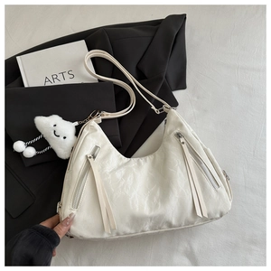 Detail of white pleated hobo bag featuring tassel zippers and cloud plush keychain charm