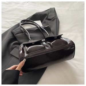 Detail view of dark brown glossy shoulder bag with double flap pockets and straps