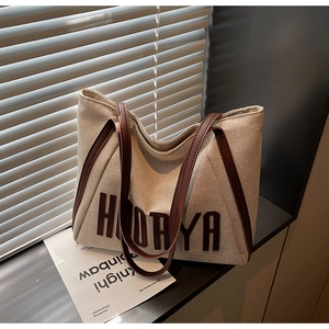 Close-up of canvas tote bag with HODAYA lettering and dark brown leather shoulder strap
