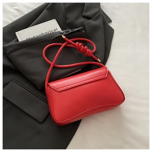 Detail of red leather rectangular handbag with knotted rope strap on black blazer