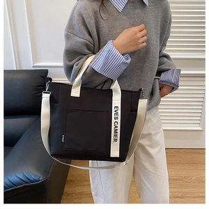 Detail of a black canvas lunch bag with cream handles and adjustable shoulder strap