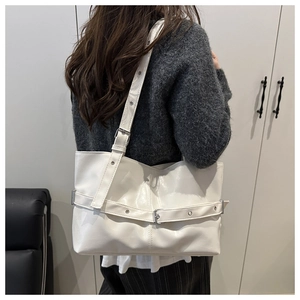 Modern white tote bag worn by a model showcasing large capacity and adjustable metal buckle