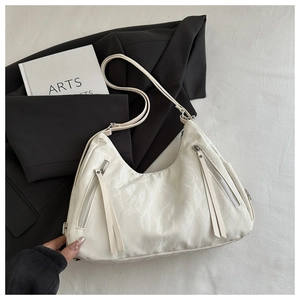 Close-up of white tote bag with elegant pleated texture and dual tassel zippers