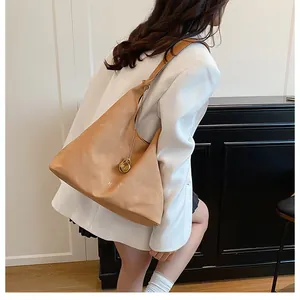 Dettaglio della grande borsa hobo color cammello in pelle morbida con ciondolo dorato